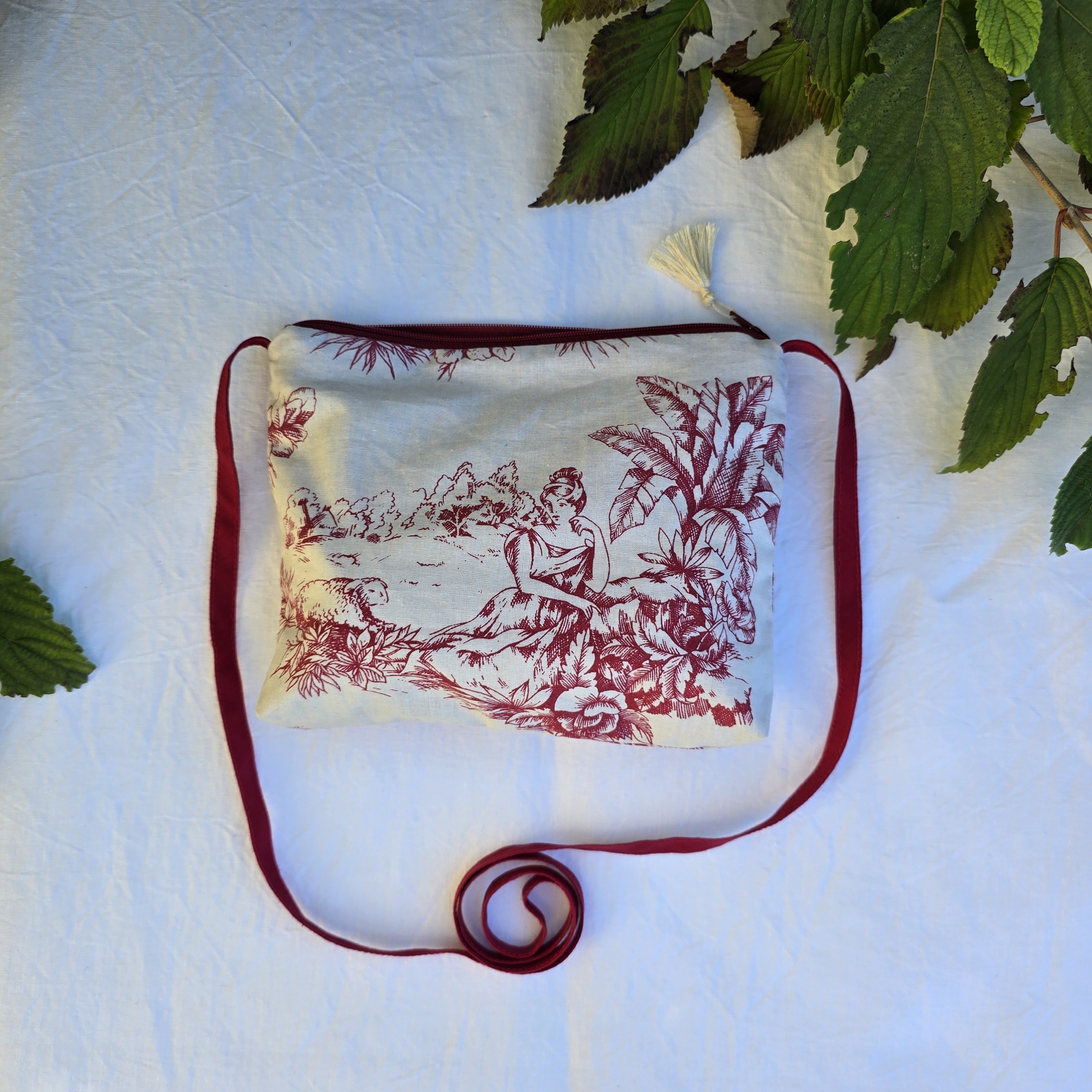 Pochette avec bandoulière en tissu toile de Jouy bordeaux et écru agrémentée d'un pompon