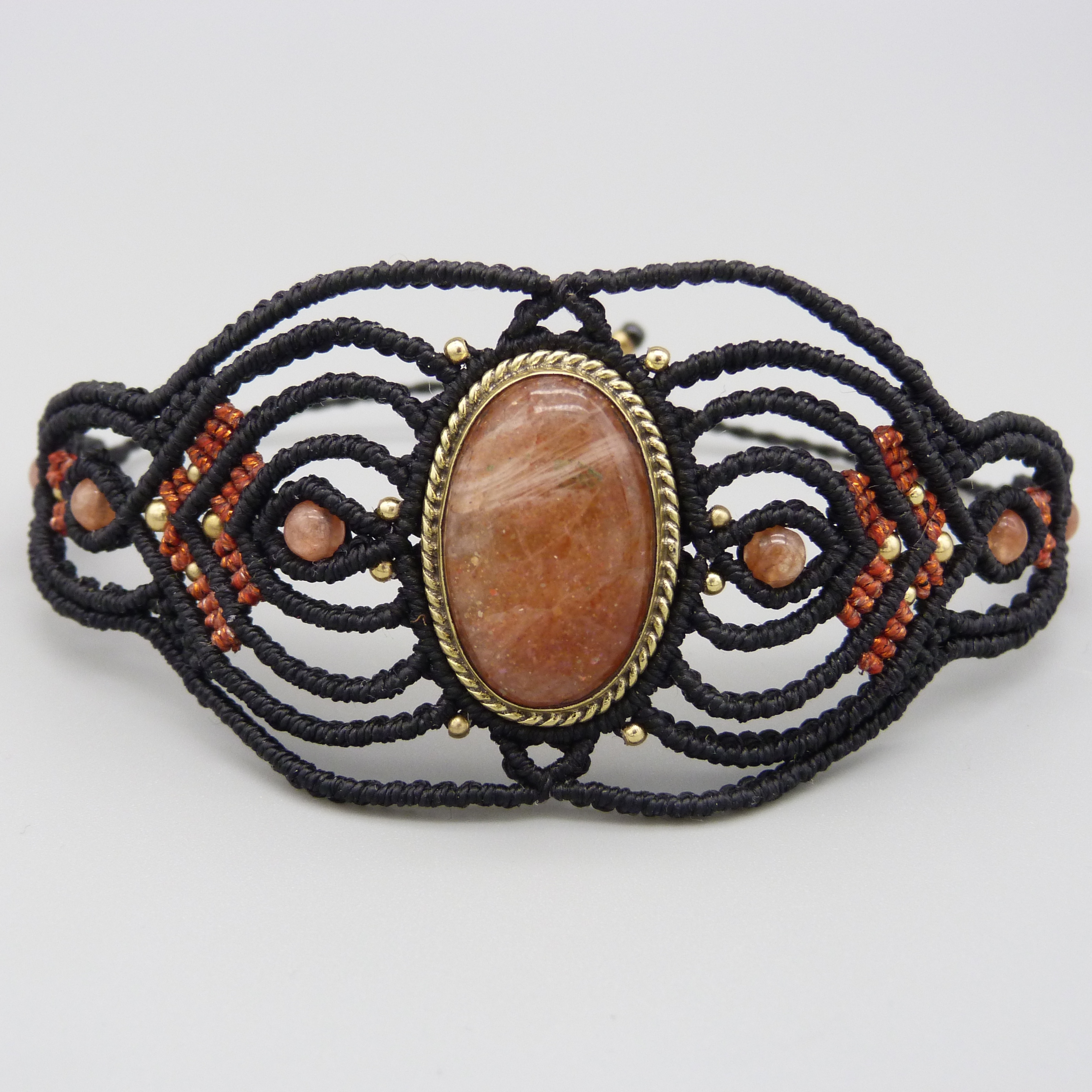 Manchette noire en micro-macramé avec une pierre de soleil