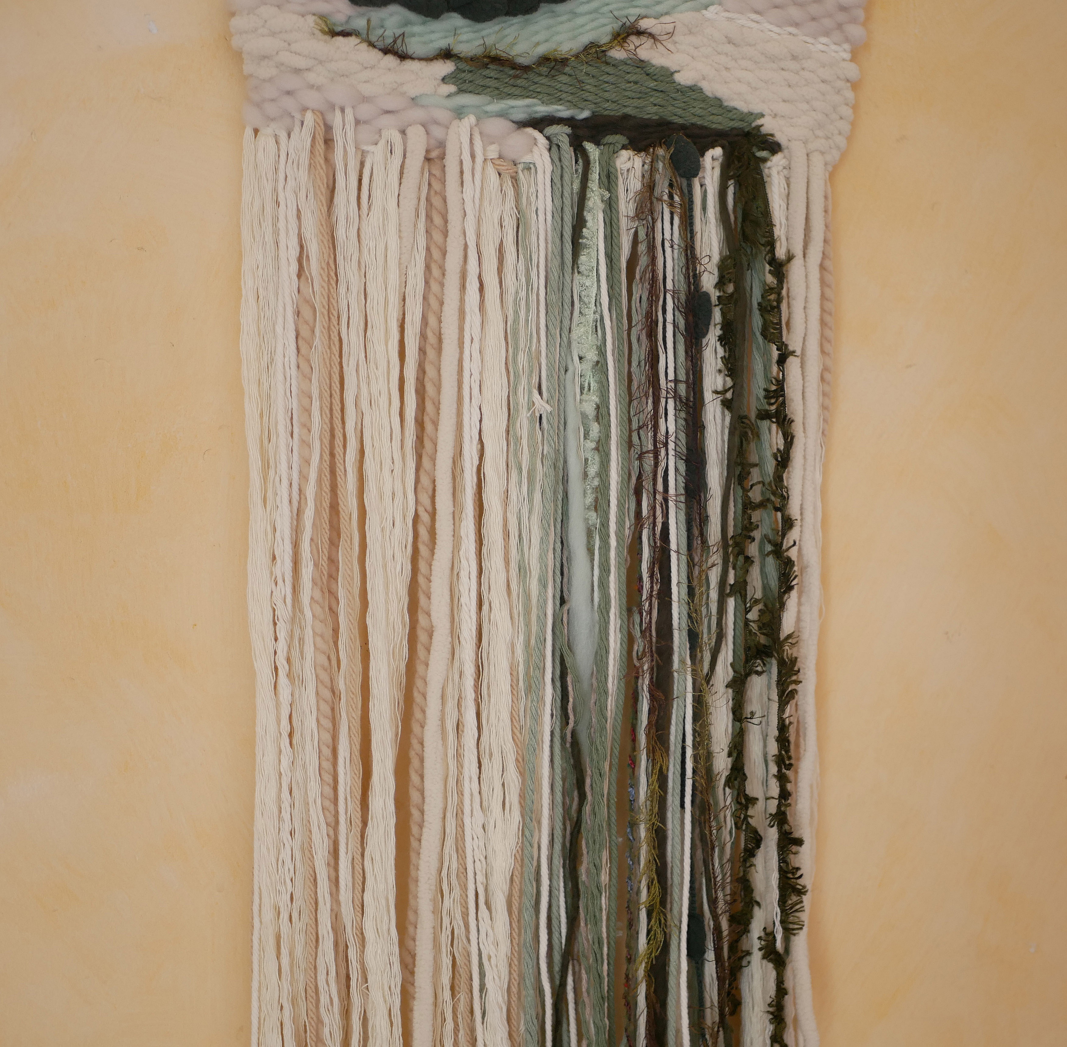 Suspension tissage mural "Les rivi&egrave;res v&eacute;g&eacute;tales" en laines et coton de couleurs vert d'eau et longues franges