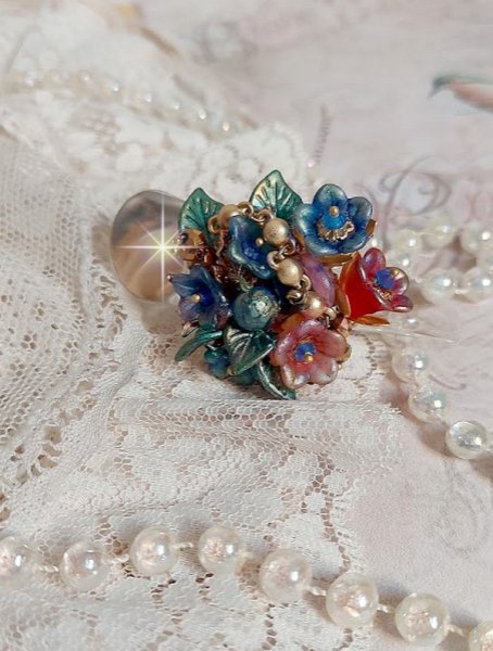 Bague Bel Air montée avec des fleurs lucites peintes à la main aux couleurs : Bleu, Rose, Rouge, Argent, Blanc avec feuilles ondulées Vert Cuivré à laquelle s’ajoute perles Dorées en Verre