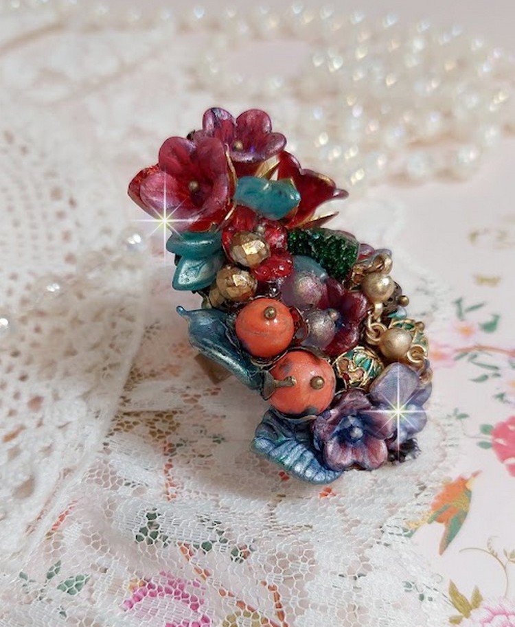 Bague Onia pour une composition florale créée avec des cristaux, fleurs : perles, clochettes, pensées, gouttes Druzy,  pierre de gemme : le Corail, perles cloisonnées et bague ovale en Laiton