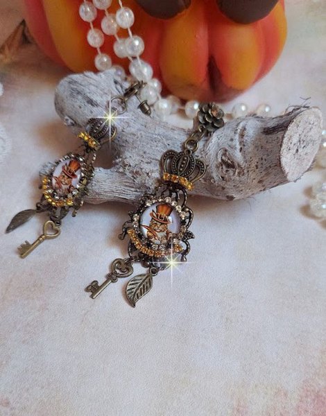 BO Chatibo Steampunk mont&eacute;es avec cabochons ronds en verre repr&eacute;sentant un chat chapeaut&eacute; Haute de Forme Orange. Strass&eacute;es avec une couronne, breloques cl&eacute;s et feuilles. Mont&eacute;es sur clips Bronze