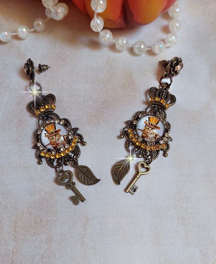 BO Chatibo Steampunk montées avec cabochons ronds en verre représentant un chat chapeauté Haute de Forme Orange. Strassées avec une couronne, breloques clés et feuilles. Montées sur clips Bronze