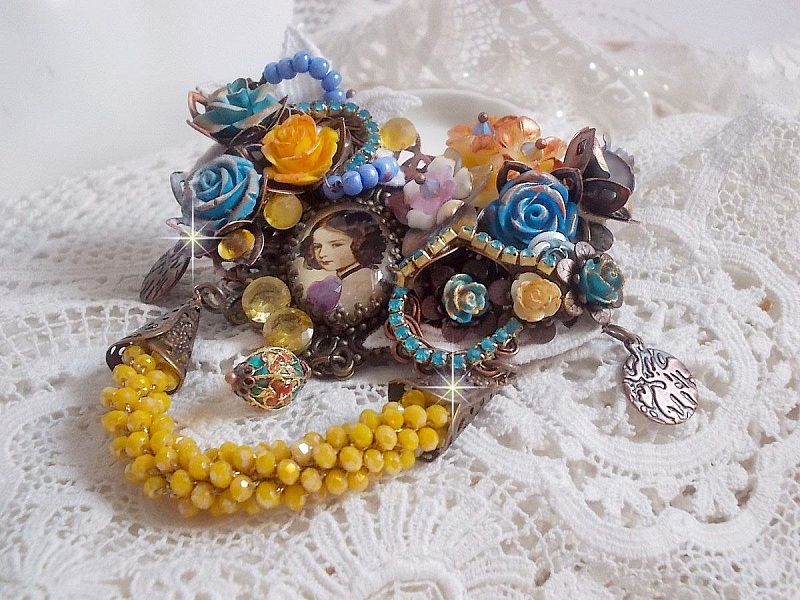 Broche artisanale baroque ornée de fleurs et perles jaunes.