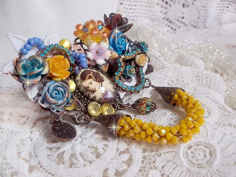 Broche artisanale baroque ornée de fleurs et perles jaunes.