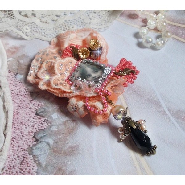 Rustik Rose broche skabt med en cabochon, der forestiller en smilende pige, orange rhinestone og Rose blonder, krystaller, glasperler og diverse tilbeh&oslash;r