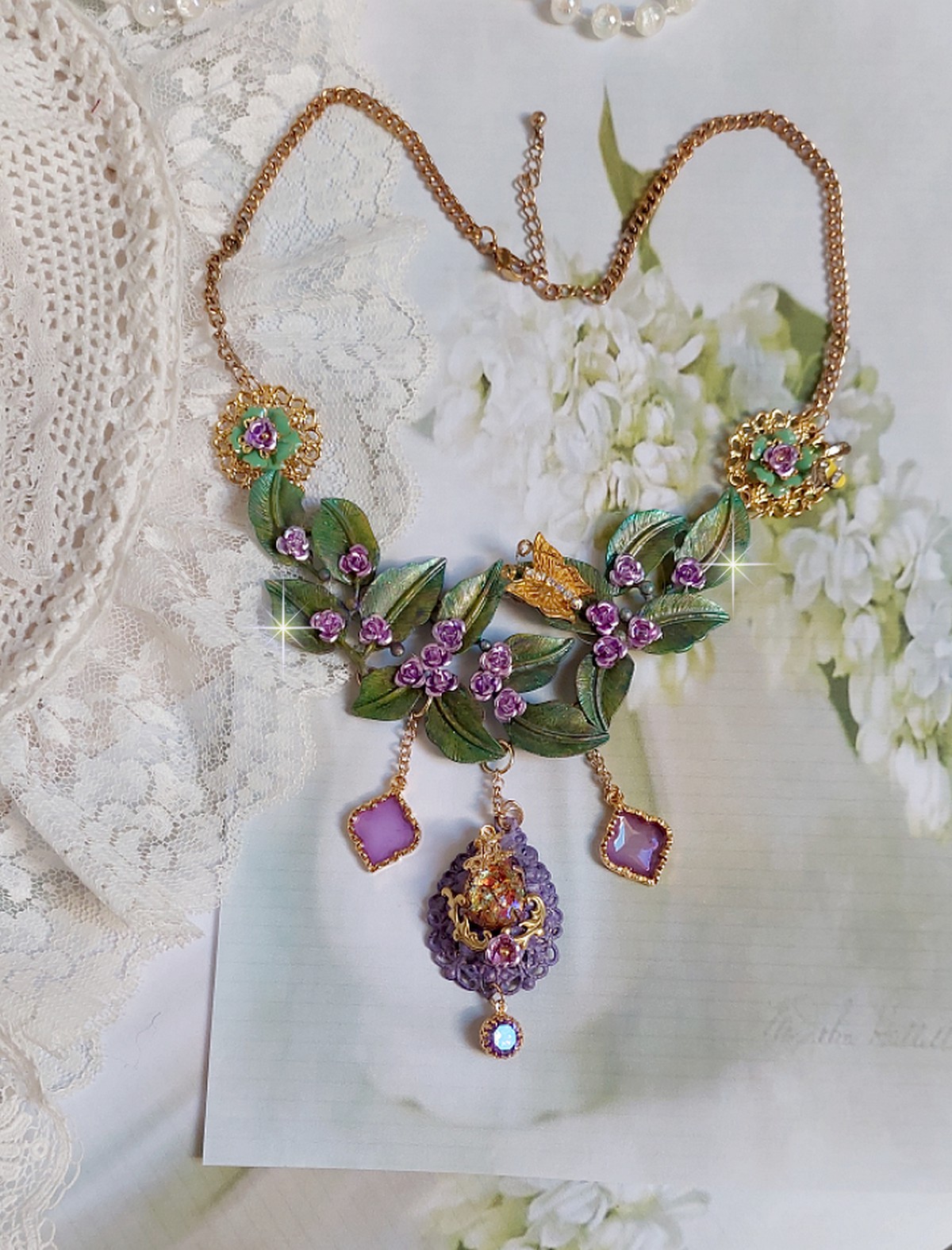 Collier Camélia Japonica monté avec un motif feuilles aquarellés à la main, paillettes, breloques papillons et abeille, roses métal, cabochon cristal, pendentifs époxy aux couleurs d’arc en ciel