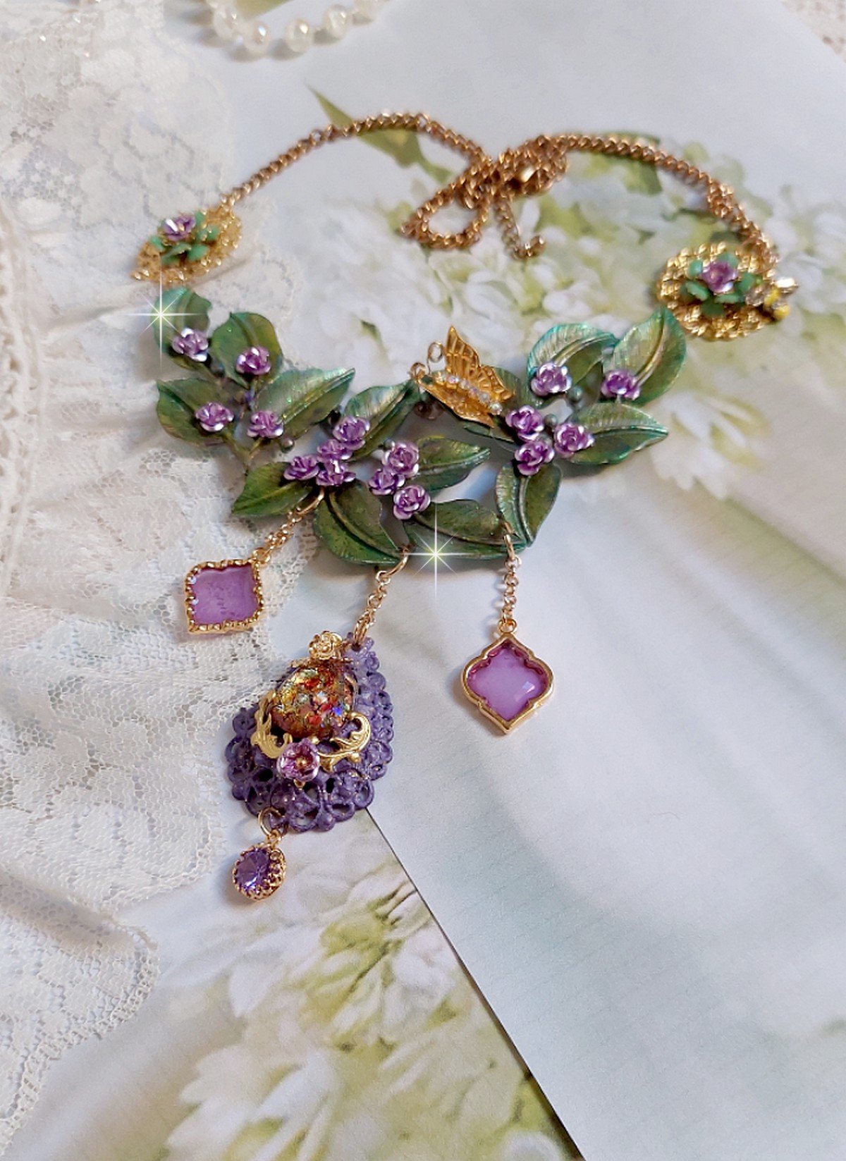 Collier Cam&eacute;lia Japonica mont&eacute; avec un motif feuilles aquarell&eacute;s &agrave; la main, paillettes, breloques papillons et abeille, roses m&eacute;tal, cabochon cristal, pendentifs &eacute;poxy aux couleurs d&rsquo;arc en ciel
