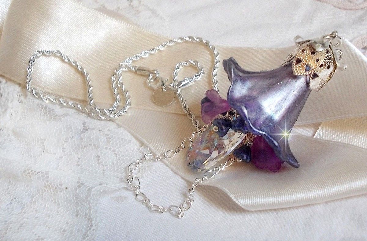 Pendentif Eclat de Cristal monté avec une goutte en Cristal, fleurs en Verre, fleurs lucites dont une plus grande peinte à la main avec paillettes Argentées. Une composition florale