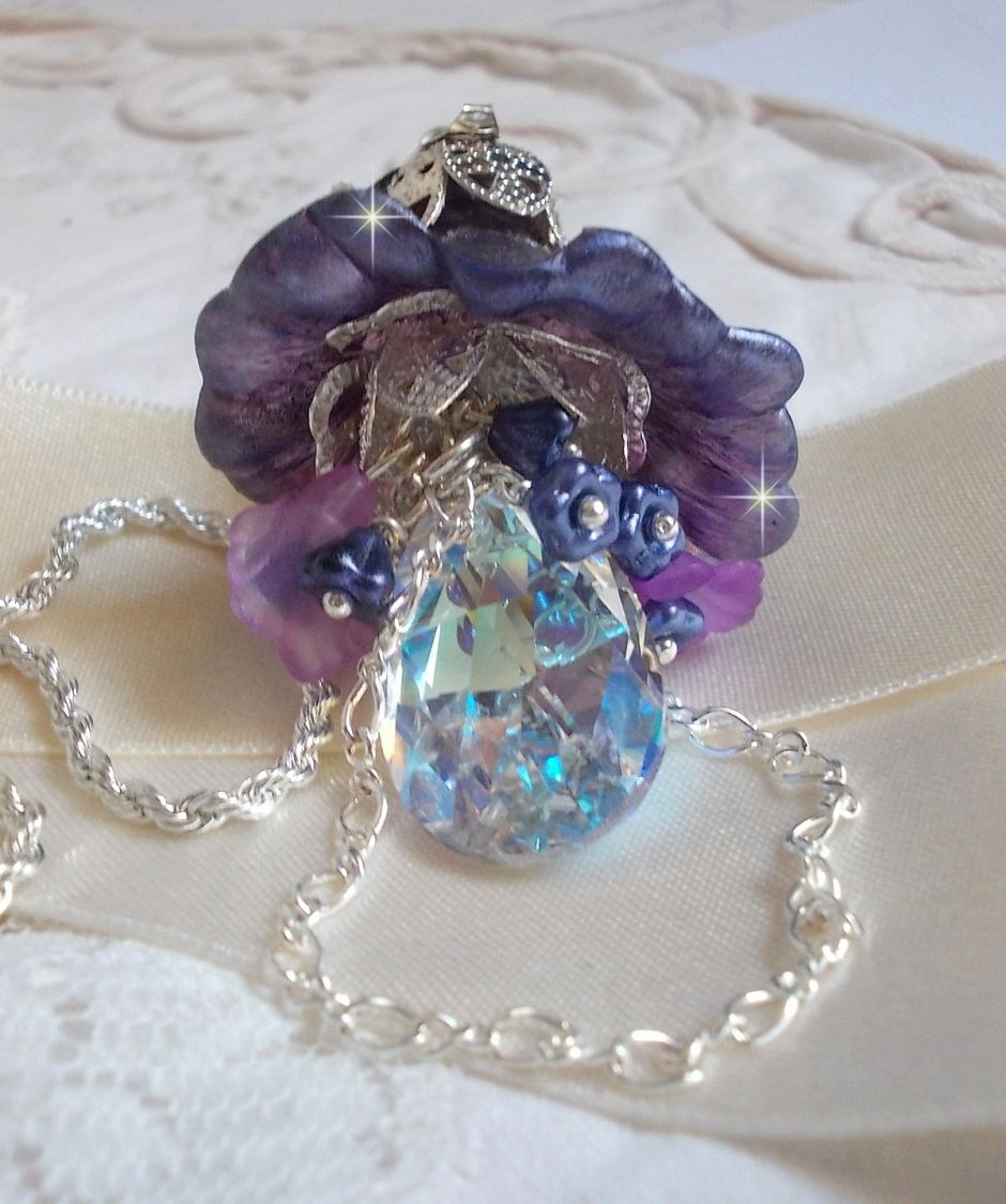 Pendentif Eclat de Cristal monté avec une goutte en Cristal, fleurs en Verre, fleurs lucites dont une plus grande peinte à la main avec paillettes Argentées. Une composition florale