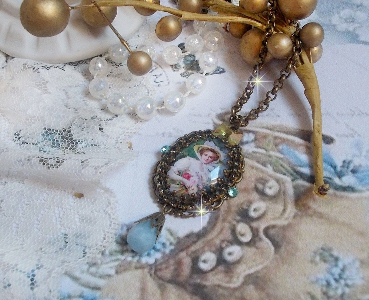 Pendentif Douce Dame créé avec un cabochon représentant une femme au chapeau blanc orné de cristaux, des accessoires de couleur Bronze et un jade teinté bleu 